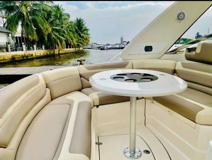 Cushioned bow seating and table on the deck of a boat beside the Lagos waterfront